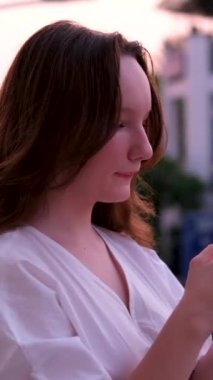 Güzel Kadın Ayakta Duruyor, Gece Parlayan Şehir Caddesinde Akıllı Telefon Kullanıyor. Gülümseyen Güzel Kadın cep telefonu kullanıyor. Dolly Sinematik Fişek Çekimine Orta Yol