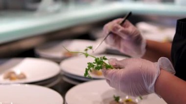 Moleküler mutfak. Şef maydanozla dekore ediyor. Moleküler mutfak malzemelerinin içinde özdeş mantar ezmesi parçaları bırakıyor. Cımbızla düzgün çalışıyor.