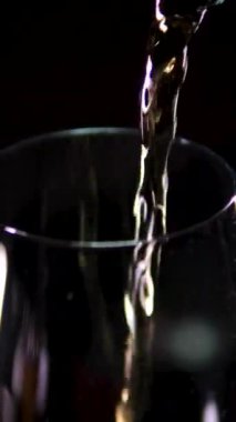 Turuncu arka planda boş bardak ve ağır çekimde köpüklü soğuk sarı bira. alkollü içecekler