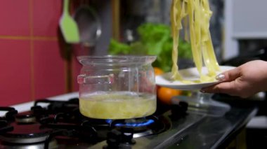 Hassas spagettiyi pişirmek için ince makarna yuvaları eklendiği için tencerede su kaynıyor. Yuva şeklinde ince spagetti erişteleri. Hazır şehriye. makarna yuvaları. Aşçılık süreci adım adım
