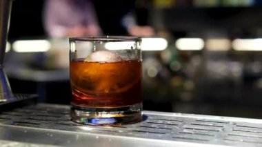 Siyah zemin üzerinde dönen soğutucu çelik taşlı, camlı viski. Buzlu viski.