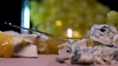 Peynirli beyaz şarap yeşil üzümlü peynir ve bal kameralı siyah arka plan yavaşça hareket ediyor. Dorblu peyniri