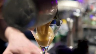 Adam masaya bir bardak espresso kokteyli koyuyor, yakın plan. Barda nefis bir espresso kokteyli, yakın plan. Ekspresso martini. Kokteyl ve kahve çekirdekleri masada.