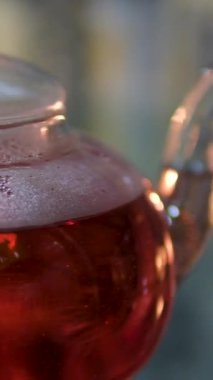 Cam bir fincanda kırmızı amber çayı ve masada kurutulmuş amber çiçeği. 