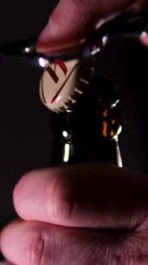 Şişe açacağıyla el açıcı bira şişesi, yakın plan, siyah arka plan