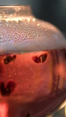 kırmızı amberçiçeği çayı. Çay topu bombasının yakın çekim videosu. Küçük porsiyonlu, kurutulmuş limon dilimli el yapımı top bombası, cam bardakta yeşil bitki çayı, dönen