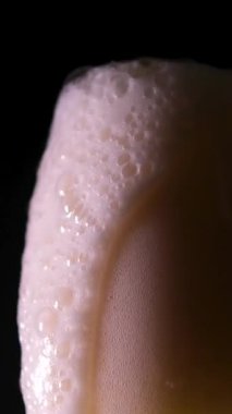 Bardağa bira dolduruyorum. Bira köpüğü dolup taşar ve siyah arkaplanda biter. 