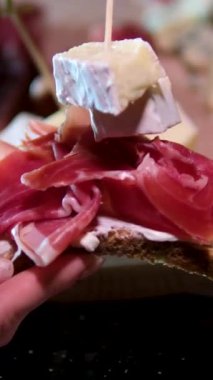 Prosciutto peynirli sandviç. Brie peyniri. Kadın eli, bir dilim ekmeğin üzerine peynir ve jambon koyarak öğle yemeği hazırlar.