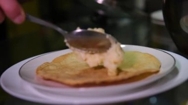 Patatesli krep servisi. Hareket animasyonunu durdur. Patates krepleri bir tabakta belirir, el ekşi krema koyar ve yeşil maydanoz ekler. Geleneksel Ukrayna mutfağı