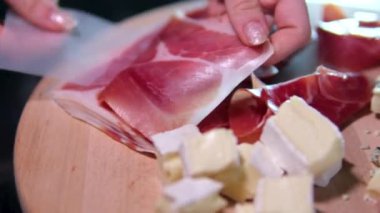 Jamon ya da kurutulmuş jambon İspanya dokusunda üretilir. 4K çözünürlüklü yiyecek. El ele verip ince bir dilim jamon al. jambon ve peynir.