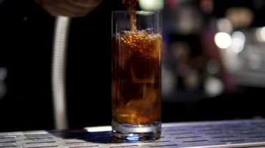 Beyaz arka planda buz küpleriyle bardağa taze kola dökülüyor. 