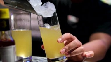 Barmen cam kapaklarına buz parçaları dolduruyor. Siyah barmen ferahlatıcı kokteyl için buz küpleri hazırlar. Bardaki ziyaretçiler için taze içecekler. alkollü içecek