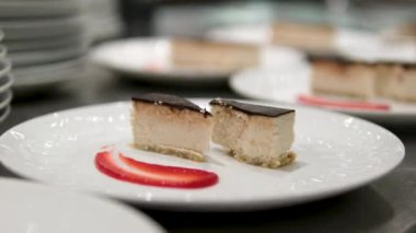 Çikolata soslu cheesecake. Çilekle süslenmiş klasik New York peynirli kekinin üzerine çikolata sosu dökülüyor.