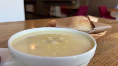 Beyaz kasede servis edilen mercimek çorbası, kiraz domatesli, soğan dilimli ve kır ekmeğiyle çiftleştirilmiş. Sıcak, dünyevi tatlar sağlıklı seçimleri kucaklıyor, nostaljik rahatlığı çağrıştırıyor..