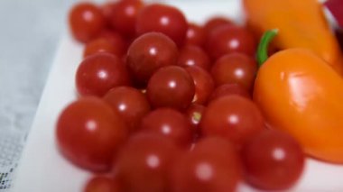 Sarı dolma biber yavaşça döner, canlı kırmızı ve sarı kiraz domateslerinin üzerinde dinlenir.