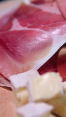 Jamon ya da kurutulmuş jambon İspanya dokusunda üretilir. 4K çözünürlüklü yiyecek. El ele verip ince bir dilim jamon al. jambon ve peynir.