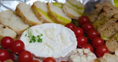  Konum. Bir ev hanımı mutfak masasındaki salataya zeytinyağı ekler. Genç bir kadın çeşitli sebze ve peynirlerle zeytinyağı döküyor. Domatesli ve kızarmış ekmekli camembert peyniri pişir.