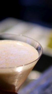 Adam masaya bir bardak espresso kokteyli koyuyor, yakın plan. Barda nefis bir espresso kokteyli, yakın plan. Ekspresso martini. Kokteyl ve kahve çekirdekleri masada.