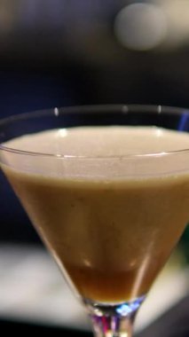 Adam masaya bir bardak espresso kokteyli koyuyor, yakın plan. Barda nefis bir espresso kokteyli, yakın plan. Ekspresso martini. Kokteyl ve kahve çekirdekleri masada.