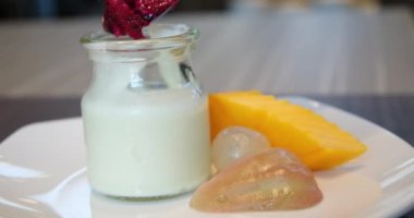 Meyveli yoğurt kaymak, muz, mango, nar ve papaya dilimleriyle karıştırılmış tatlı bir tatlı tabağı. pitahaya kırmızı ejderha meyvesi