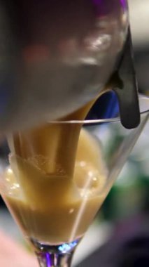 Adam masaya bir bardak espresso kokteyli koyuyor, yakın plan. Barda nefis bir espresso kokteyli, yakın plan. Ekspresso martini. Kokteyl ve kahve çekirdekleri masada.