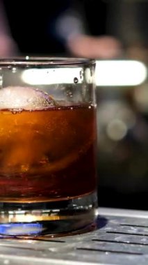 Siyah zemin üzerinde dönen soğutucu çelik taşlı, camlı viski. Buzlu viski.