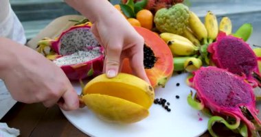 Ağır çekimde kadın taze mango meyvesi kesiyor ve doğranmış posanın sulu tarafını gösteriyor..