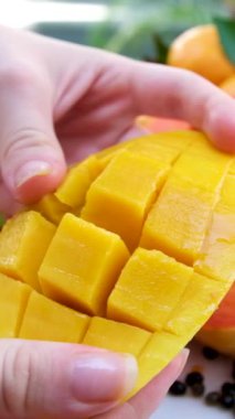 Ağır çekimde kadın taze mango meyvesi kesiyor ve doğranmış posanın sulu tarafını gösteriyor..
