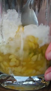 Geleneksel Endonezya aperatifi Es Campur 'la bir kaşık tutan bir kişi. Çim jölesi sergiliyor ve bu popüler tatlının canlandırıcı, renkli özelliklerini vurguluyor..