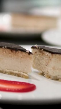 Çikolata soslu cheesecake. Çilekle süslenmiş klasik New York peynirli kekinin üzerine çikolata sosu dökülüyor.