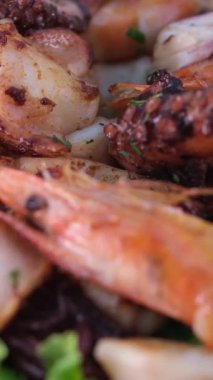 Lezzetli bir tabak deniz ürünü ve kumsala bakan bir masada kızarmış balık.