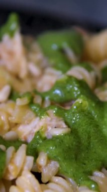 Domatesli fusilli makarna, koyu gri kasede fesleğen, üst görüş, siyah arka planda izole edilmiş, dönüşlü, makro yakın çekim.. 