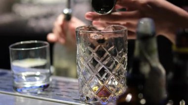Profesyonel barmenin bar ya da salon kulübündeki müşterilerle alkollü bir kokteyli kristal uzun süreli buz küpleriyle karıştırması..