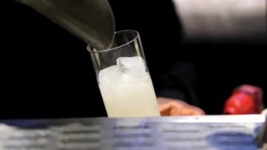 Barmen cam kapağına kepçeyle buz dolduruyor. Siyah barmen ferahlatıcı kokteyl için buz küpleri hazırlar. Bardaki ziyaretçiler için taze içecekler