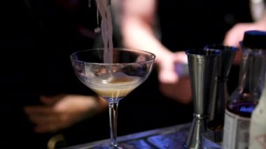 Bakır karıştırıcıdan martini bardağına bir kokteyl dökmek, profesyonel bir ortamda bar hazırlamak zarif bir cam ve pürüzsüz bir infaz.