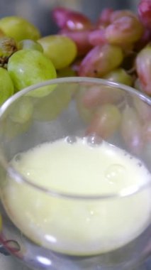 Taze harmanlanmış, tohum ve bardaktaki deri parçalarıyla dolu kalın üzüm suyu. Cam bir kasede üzüm demetleri ve masada üzümlü meyveler. Aspirin tableti bardakta köpürüyor.