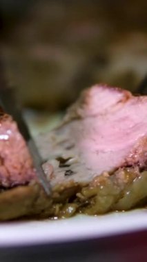 Şef taze ızgara et dilimliyor. Mutfaktaki ahşap kesme tahtasının üzerinde bıçakla. Yemekler yakınlaştırılıyor.