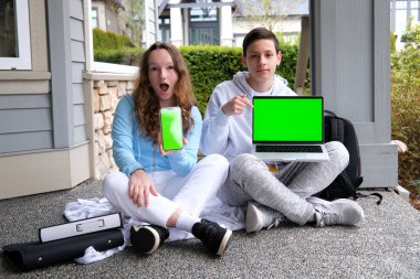 Okul çağındaki erkek ve kız çocukların kesilmiş görüntüsü. Merdivenlerde oturan ortaokul öğrencileri ve dijital cihazlar kullanıyorlar. Kablosuz bilgisayarlı tablet akıllı telefon. 