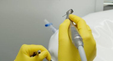 Ameliyathanede cerrahi aletler var. Ameliyat kıyafeti ve eldiven giymiş bir hemşire diş implantı ameliyatı için hazırlanıyor. Diş araştırması, cımbız, neşter, iğne tutacağı, enstrümandaki Rasps. 