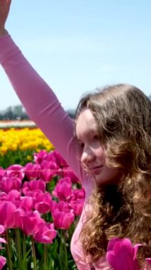 Gün ışığında pembe çiçek bahçesinde dikilen gündelik elbiseli genç bir kadın. Baharda el ele tutuşan hayalperest kız güneş ışınlarıyla çiçek açan parkta. Güzel bayan fotoğrafçı lalede eğleniyor.