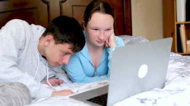 Genç bir kadının kolej yurdunda yerde oturup dizüstü bilgisayarda yazarken orta boy fotoğrafı, sonra da kız arkadaşına yatakta uzanmış ve cep telefonu kullanırken bir şeyler gösteriyor. Konuşuyorlar ve gülümsüyorlar. 4k 