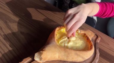 Kadınların elleri Adjarian Khachapuri 'den bir parça koparıp erimiş peynir ve yumurta sarısı karışımına batırıyor. Geleneksel Gürcü yemek kavramının tadını çıkarıyorum. Yüksek kalite 4k görüntü