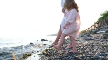 Mutlu, gülümseyen küçük kız sahilde çıplak ayakla deniz kenarında vakit geçirir, deniz dalgalarıyla oynar tatilde okyanusun tadını çıkarır. Çocuklar yaz tatili seyahatinde eğlenerek oynarlar. Rahatlayın sağlık. Pozitif 