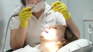 Diş muayenesinde hasta dişlerini muayene eden deneyimli bir diş hekimi. Maske takan profesyonel bir kadın doktor detaylı bir oral tedavi uyguluyor. Stomatoloji prosedürü dişçilikte sağlanır 
