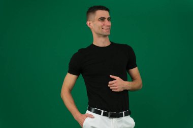 Gri arka plandaki yakışıklı genç adam kameraya bakıyor. Gri duvara yaslanmış elleri ceplerinde gülen genç adamın portresi. Mutlu adam gülümsüyor. Yüksek kalite fotoğraf