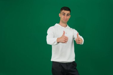 Mor kazak giyen genç Hintli adam izole edilmiş pembe arka plan başarısı tabelasının üzerinde duruyor. Elleriyle olumlu jest yapıyor, gülümsüyor ve mutlu. Neşeli ifade ve kazanan