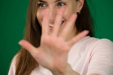 Kendini ifade eden bir kadın. Yeşil arka plan renginde genç bir kızın farklı duyguları güzel yüz hatları gerçek insanların pembe tişörtlü beyaz tenleri. Avrupa