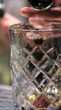 Profesyonel barmenin bar ya da salon kulübündeki müşterilerle alkollü bir kokteyli kristal uzun süreli buz küpleriyle karıştırması..