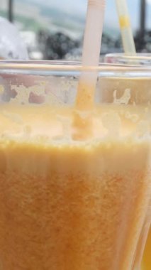 İştah açıcı portakal suyu, kesilmiş portakalların arka planına karşı bardakta dalgalanıyor. Yüksek kalite 4k görüntü