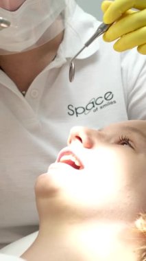 Diş muayenesinde hasta dişlerini muayene eden deneyimli bir diş hekimi. Maske takan profesyonel bir kadın doktor detaylı bir oral tedavi uyguluyor. Stomatoloji prosedürü dişçilikte sağlanır 